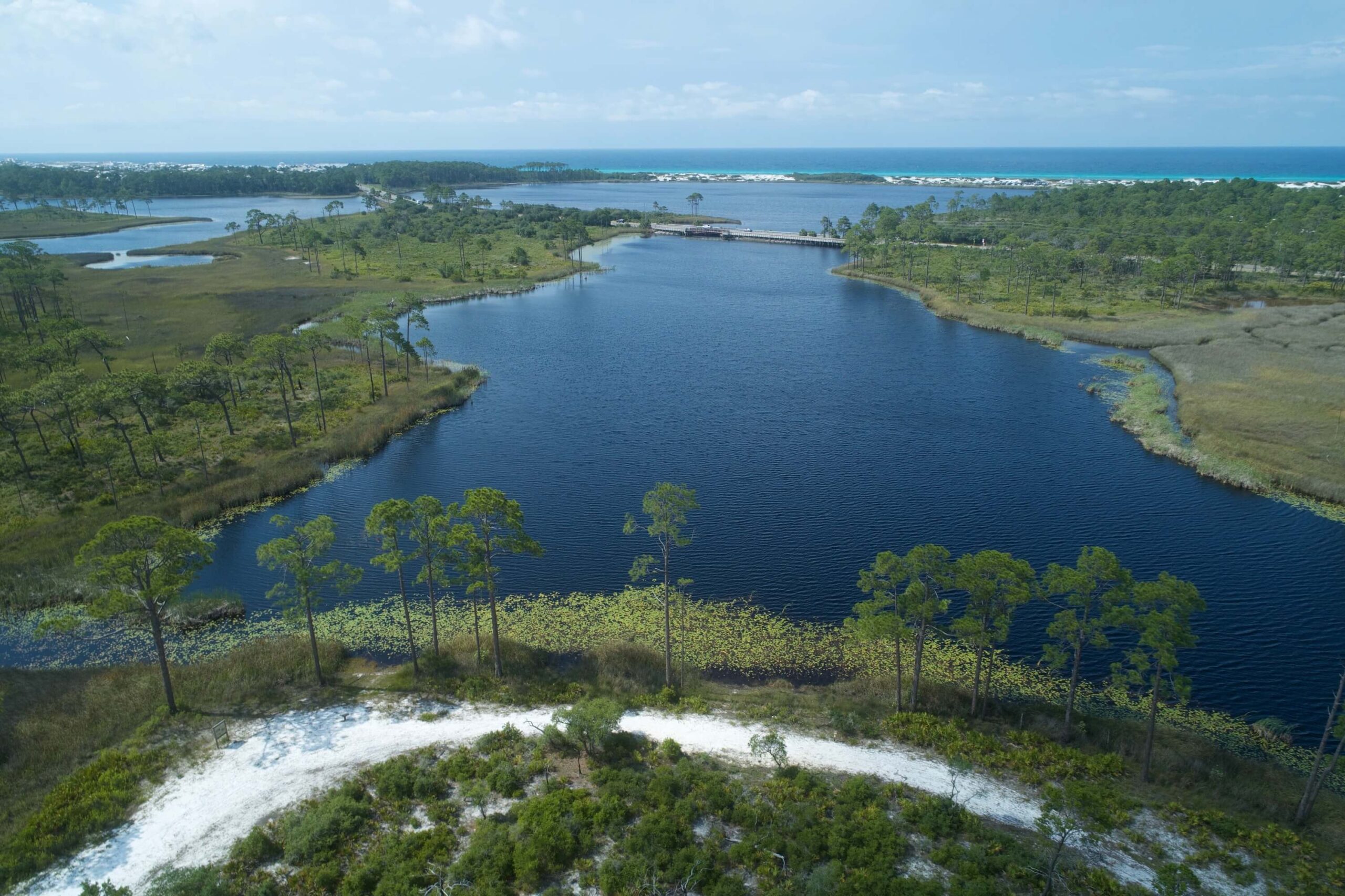 A scenic view of Santa Rosa Beach, FL, featuring white sandy shores, dune lakes, and a clear blue sky.